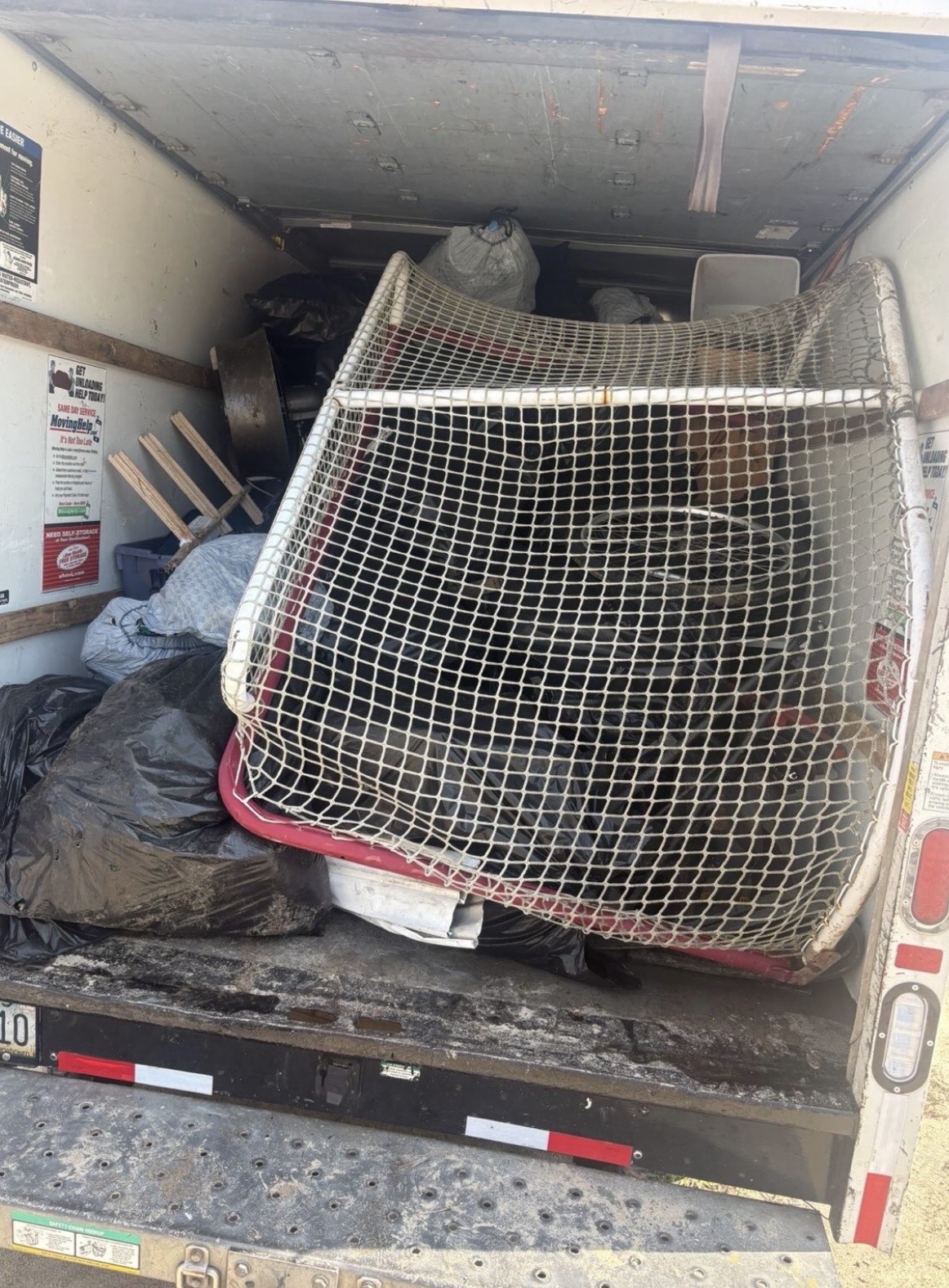 Back of The Clear Out Crew truck packed full of removed furniture, bags, and debris